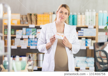 Pregnant woman pharmacist offering pills 131408756