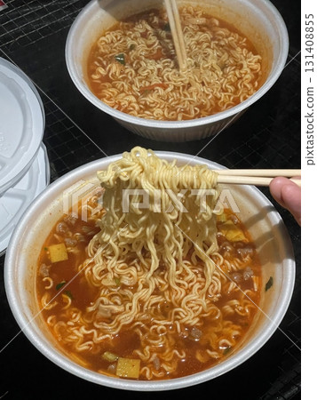 A steaming cup of ramyeon, featuring flavorful noodles and rich broth. Perfect for quick meals or snack-related projects, capturing the essence of comfort food in a convenient, portable format. A steaming cup of ramyeon, featuring flavorful noodles and rich broth. Perfect for quick meals or snack-related projects, capturing the essence of comfort food in a convenient, portable format. 131408855