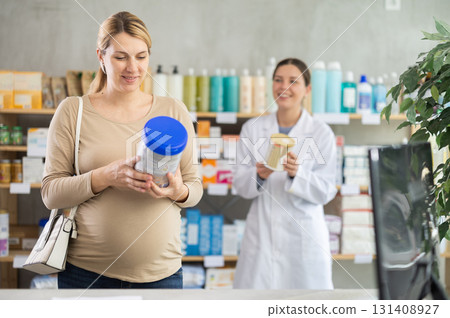 Expecting mother checking baby formula label while pharmacist offering alternative 131408927