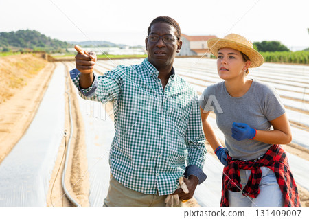 African american farmer giving instructions to female worker at farm field African american farmer giving instructions to female worker at farm field 131409007