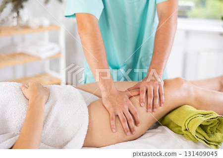 Anti cellulite thigh massage in the salon close-up. Masseur doing leg massage to woman 131409045