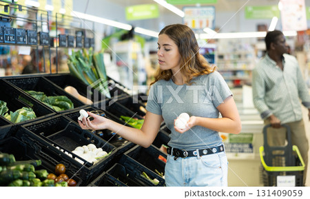 Young woman choosing mushrooms in grocery store 131409059