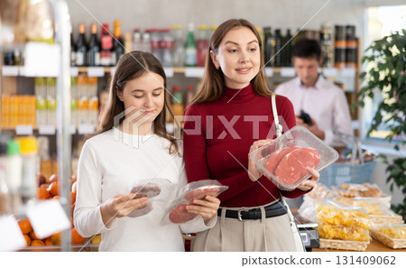 Woman and her teenage daughter choosing hamburger or beef entrecote in grocery Woman and her teenage daughter choosing hamburger or beef entrecote in grocery 131409062