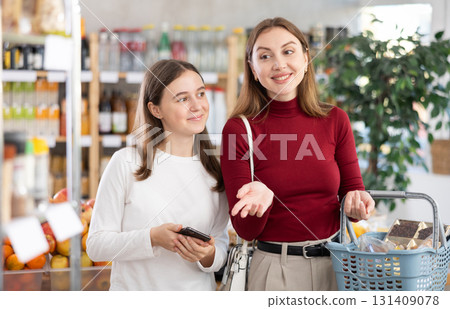 Teenage girl and her mother choosing some products in grocery Teenage girl and her mother choosing some products in grocery 131409078