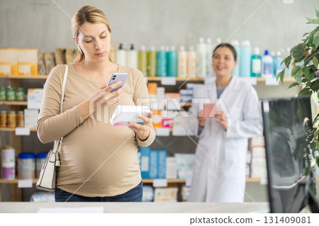 Pregnant woman scan QR code on vitamin pills product, pharmacist offer similar product in background 131409081