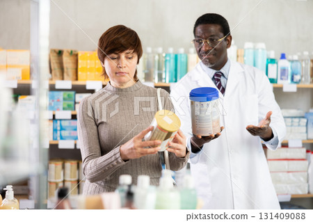 Woman choosing baby formula with help from pharmacist Woman choosing baby formula with help from pharmacist 131409088