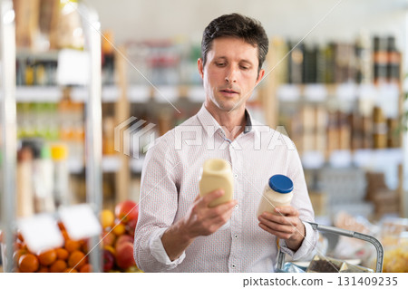 Man in light shirt choose and buy mayonnaise in store Man in light shirt choose and buy mayonnaise in store 131409235