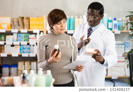 Woman choose buy antitussive syrup at pharmacy. African man in background 131409237
