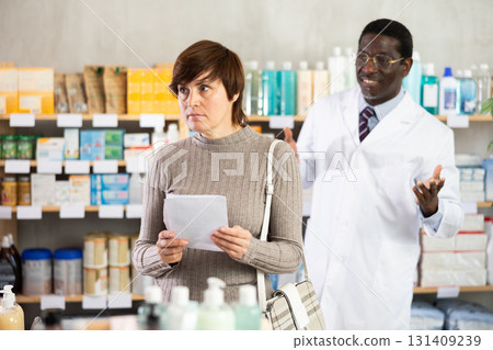 Woman choosing prescription medications with help of pharmacist 131409239
