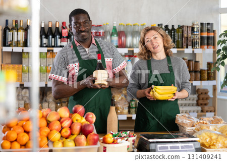 Positive female and male sellers offers choice of various natural food in grocery supermarket 131409241