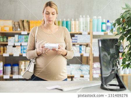 Pregnant woman chooses pills at pharmacy Pregnant woman chooses pills at pharmacy 131409276