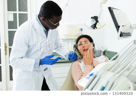 Woman patient complaining to male dentist about toothache at dental clinic 131409320