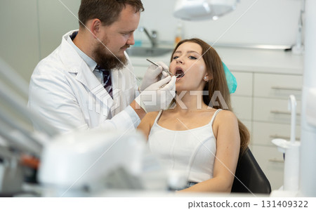 Male dentist checking the teeth of a woman in the office 131409322