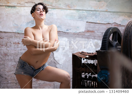 Pretty girl wear t-shirt and blue short sexy looking near old machine tools 131409460