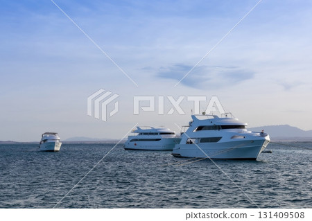 Serene coastal scene with luxury yachts anchored in tranquil blue waters Serene coastal scene with luxury yachts anchored in tranquil blue waters 131409508
