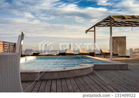 Rooftop oasis with swimming pool and lounge chairs against blue sky Rooftop oasis with swimming pool and lounge chairs against blue sky 131409522