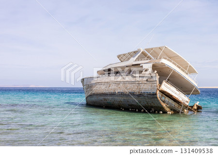 Abandoned shipwreck on tranquil seashore with crystal clear water and blue sky 131409538