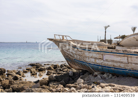 Weathered boat on rocky shore by a calm sea, evoking tranquility and nostalgia 131409539