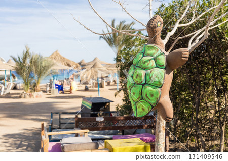 Tropical beach scene with vibrant turtle sculpture and relaxing atmosphere Tropical beach scene with vibrant turtle sculpture and relaxing atmosphere 131409546