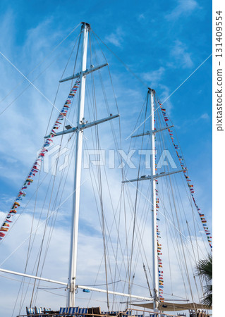 Majestic sailing ship masts with colorful flags against blue sky Majestic sailing ship masts with colorful flags against blue sky 131409554