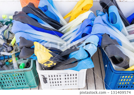 Collection of colorful snorkeling fins and gear in plastic bins on deck Collection of colorful snorkeling fins and gear in plastic bins on deck 131409574