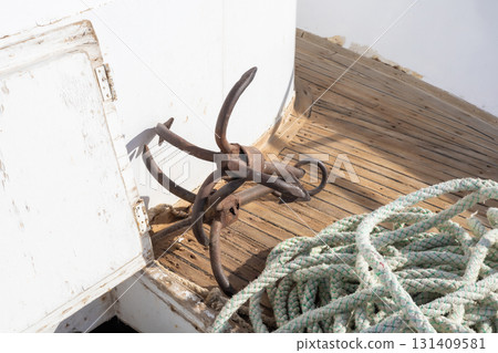 Vintage nautical anchor and rope on weathered wooden deck 131409581