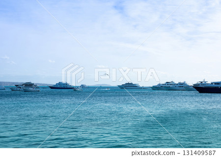 Serene seascape with boats on clear blue water under bright sky Serene seascape with boats on clear blue water under bright sky 131409587