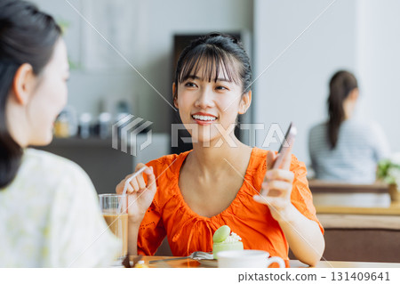 一位年輕女子在咖啡館用智慧型手機聊天 一位年輕女子在咖啡館用智慧型手機聊天 131409641