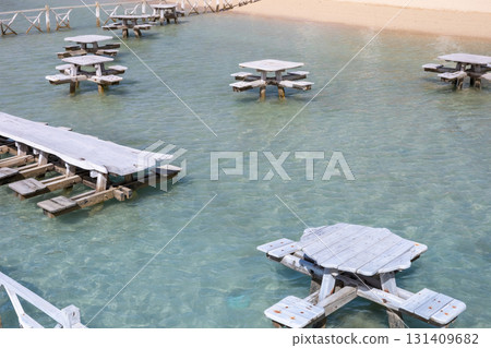Serene beach scene with floating picnic tables in tranquil turquoise water 131409682