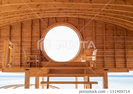 Cozy oceanside retreat with wooden interior and scenic views through circular window Cozy oceanside retreat with wooden interior and scenic views through circular window 131409714