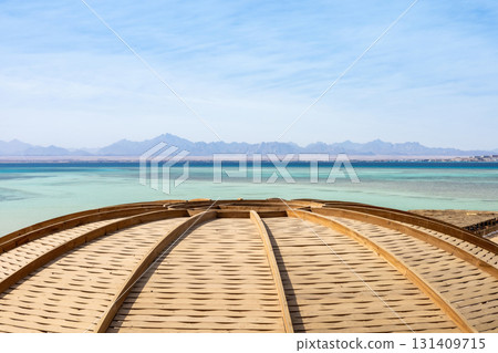 Serene coastal view with wooden dome and distant mountains in low resolution Serene coastal view with wooden dome and distant mountains in low resolution 131409715