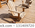 Rustic wooden adirondack chairs on sunlit deck for relaxation and outdoor leisure 131409720