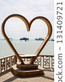 Heart-shaped sculpture overlooking tranquil sea with boats in the distance 131409721