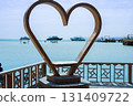Romantic beachfront scene with heart sculpture and boats on clear blue water 131409722