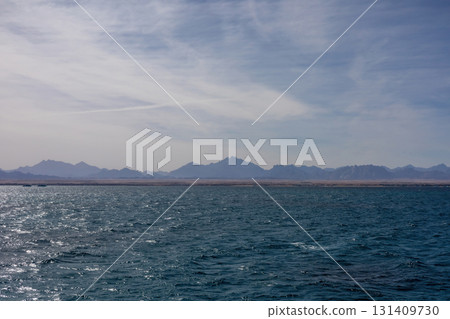 Serene ocean view with distant mountain range and clear sky Serene ocean view with distant mountain range and clear sky 131409730
