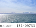 Tranquil coastal landscape with blue ocean and distant mountains under a clear sky 131409733