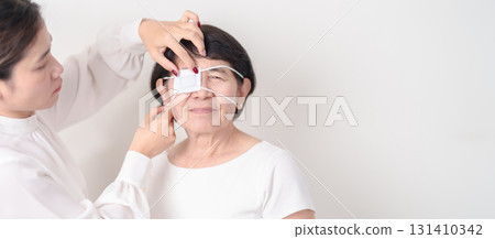 Elderly Woman with Eye protecting by Eye Pad for concepts of Eye disease, Cataract, Glaucoma, Age Related Macular Degeneration, Diabetic Retinopathy, Vitreous, Conjunctivitis, World Glaucoma day 131410342