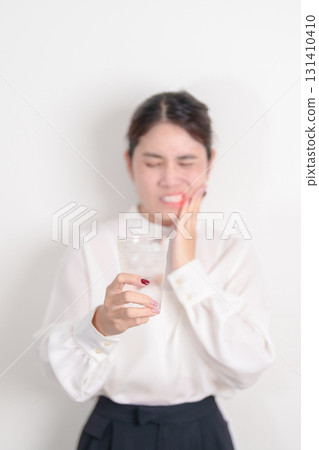 Business woman having toothache and pain after drink ice water for concept of Teeth Sensitive to Cold, Tooth Decay and Gum Disease, Grinding Teeth and Stress, Exposed Nerve Roots, Crack and Receding 131410410