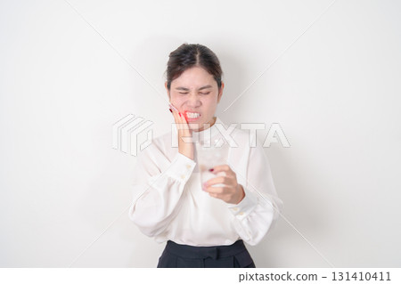 Business woman having toothache and pain after drink ice water for concept of Teeth Sensitive to Cold, Tooth Decay and Gum Disease, Grinding Teeth and Stress, Exposed Nerve Roots, Crack and Receding 131410411
