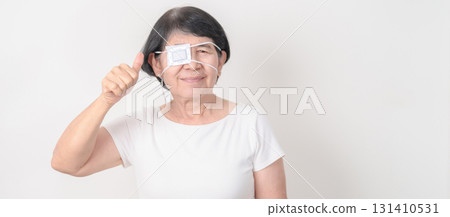 Elderly Woman with Eye protecting by Eye Pad for concepts of Eye disease, Cataract, Glaucoma, Age Related Macular Degeneration, Diabetic Retinopathy, Vitreous, Conjunctivitis, World Glaucoma day 131410531