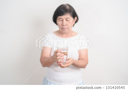 Elderly woman having Tremor hand during hold water glass. Parkinson disease April awareness month, Carpal Tunnel Syndrome, rheumatoid and brain injury, Neurological disorder and Senior health concept Elderly woman having Tremor hand during hold water glass. Parkinson disease April awareness month, Carpal Tunnel Syndrome, rheumatoid and brain injury, Neurological disorder and Senior health concept 131410545
