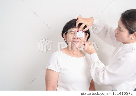 Elderly Woman with Eye protecting by Eye Pad for concepts of Eye disease, Cataract, Glaucoma, Age Related Macular Degeneration, Diabetic Retinopathy, Vitreous, Conjunctivitis, World Glaucoma day 131410572