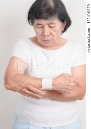Elderly Woman having wrist pain with Medicated pain relief patch plaster for Carpal Tunnel Syndrome, Wrist Tendinitis, muscle ache, De Quervain s tenosynovitis, Hand Osteoarthritis and Senior health 131410669