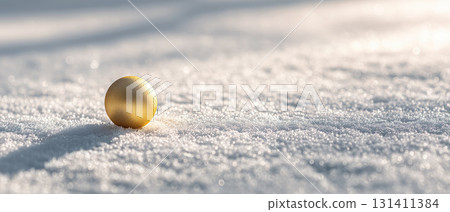 Golden ornament ball on snowy surface, soft light 131411384