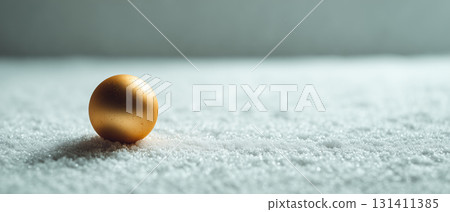 Golden ornament ball on snowy surface 131411385