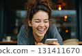 Smiling woman relaxing on sofa with smartphone, enjoying a joyful carefree moment 131411670