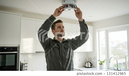 Man installs smoke detector for home safety. Important home safety check always Man installs smoke detector for home safety. Important home safety check always 131412965