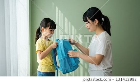 Mother shows care helping daughter with backpack. Morning routine reflects care Mother shows care helping daughter with backpack. Morning routine reflects care 131412982