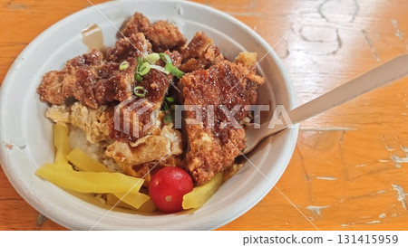 Bowl of Japanese katsudon with breaded pork cutlet, rice, egg, pickles, and sauce garnished with green onion Bowl of Japanese katsudon with breaded pork cutlet, rice, egg, pickles, and sauce garnished with green onion 131415959