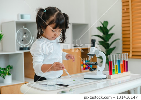 toddler girl scientist using pipette dropping of liquid being placed on glass slide, preparing specimen for science microscope 131416147